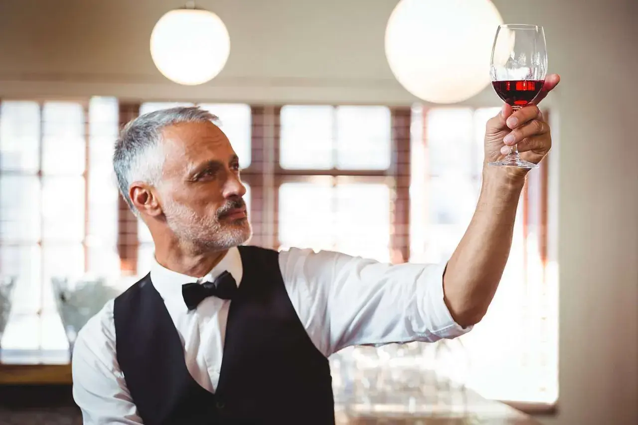 Ein erfahrener Sommelier, ein wahrer **master of wine**, prüft das tiefe Rot eines edlen Tropfens im Glas.