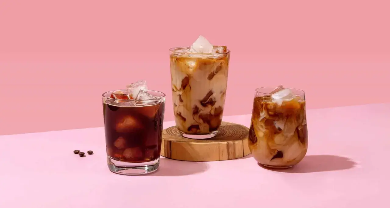 Drei Gläser mit erfrischendem Cold Brew Eiskaffee, einer mit dunklem Kaffee, die anderen beiden mit Milch und Eis.