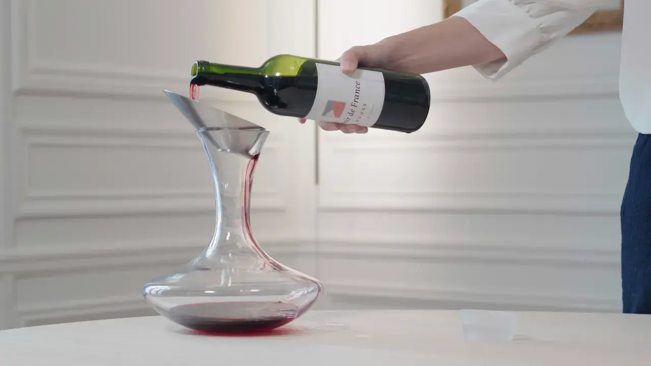 Ein Sommelier dekantiert sorgfältig Rotwein in eine Karaffe.