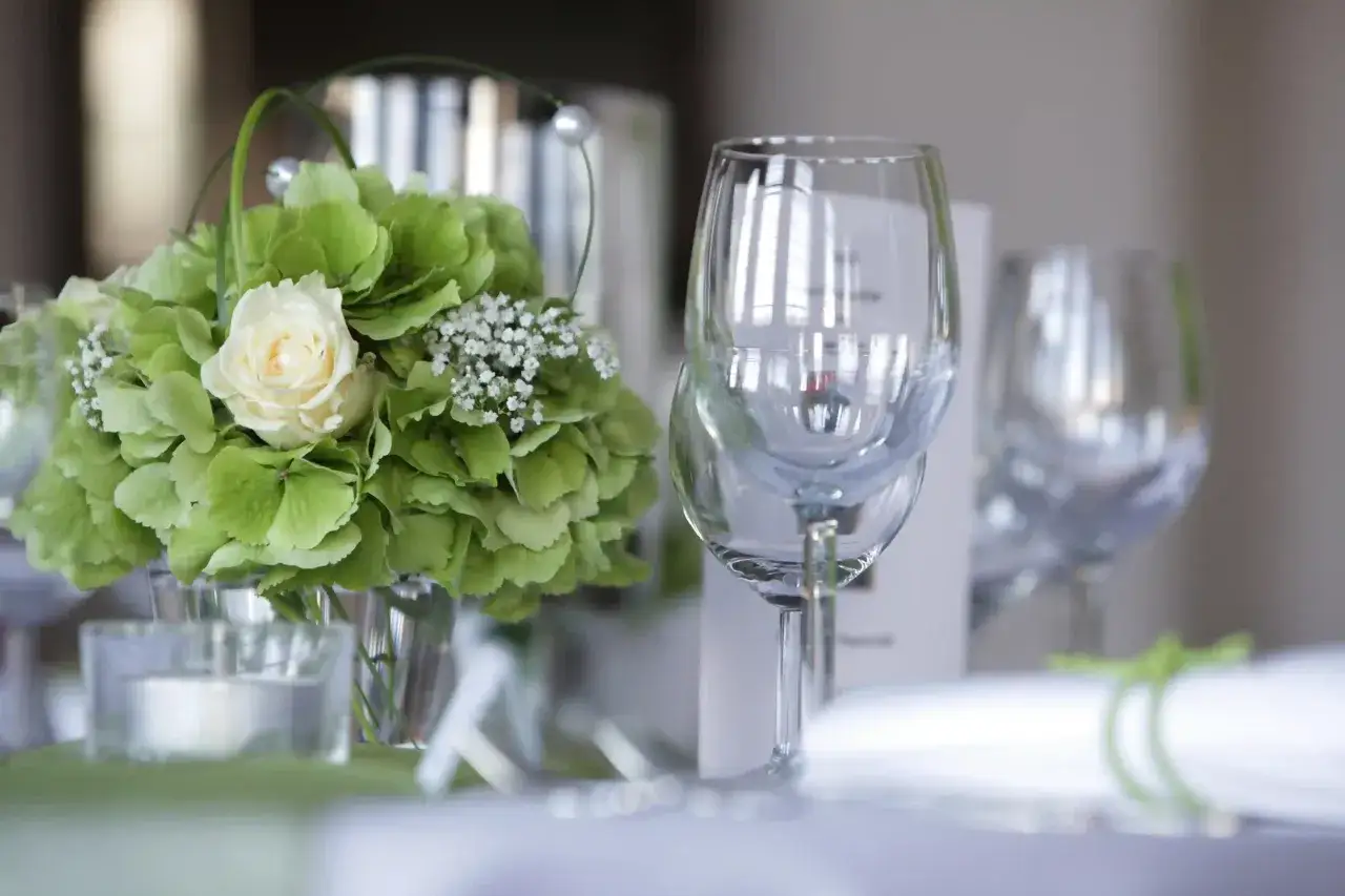 Festlich gedeckter Tisch mit Blumen und Weingläsern. Die Frage