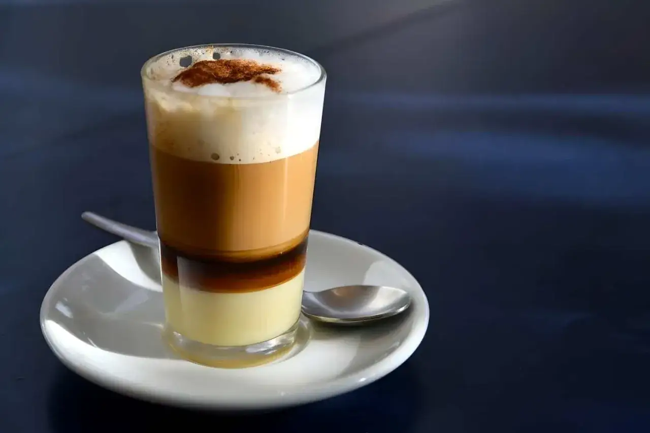 Ein geschichteter Barraquito mit Kondensmilch, Likör, Kaffee und Milchschaum, bestreut mit Zimt. Perfekt für das Barraquito Rezept.