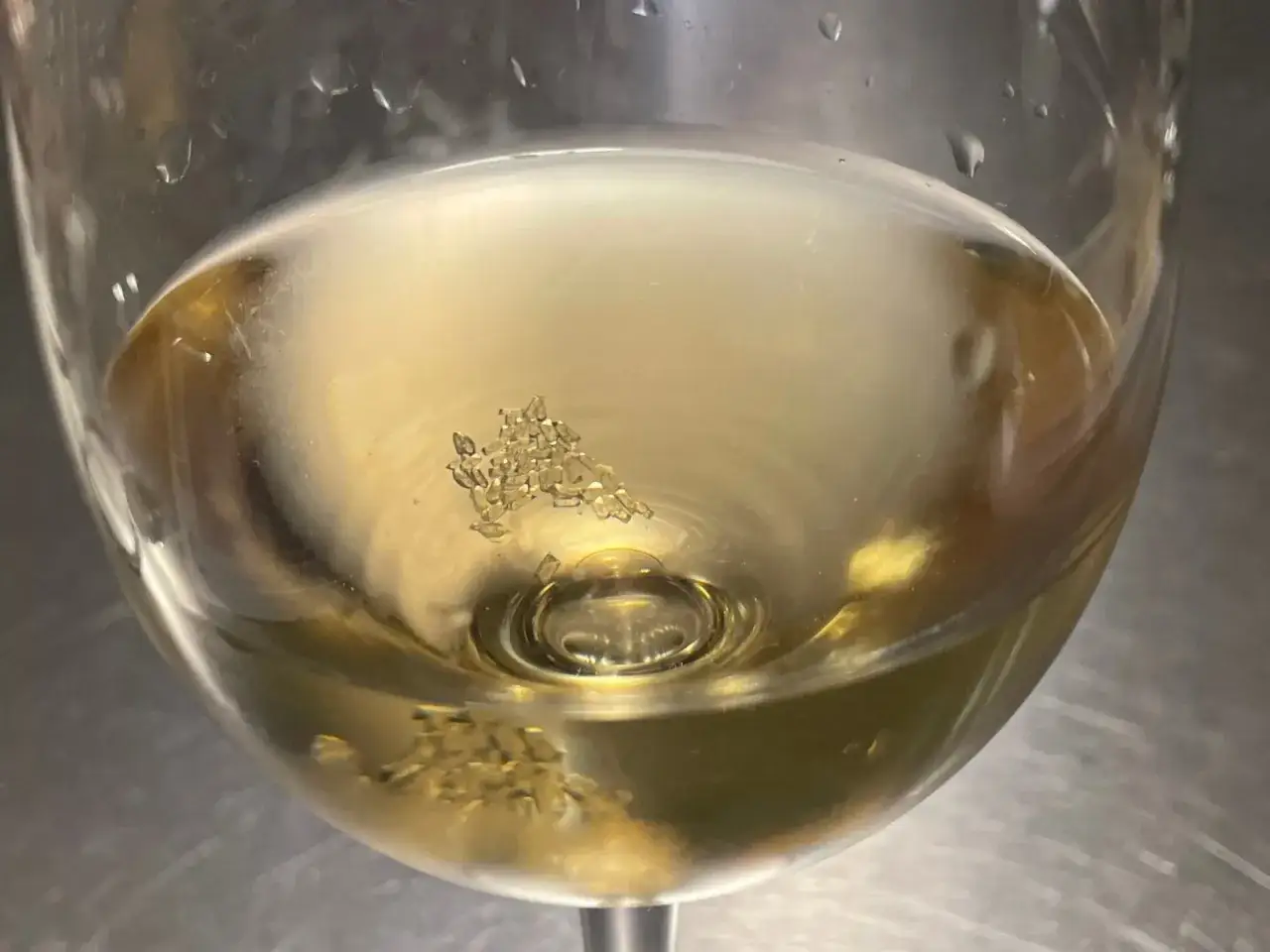 Feine Kristalle, wie kleine Diamanten, bilden sich im hellen Wein. Weinstein im Glas, ein Zeichen von Reife und Charakter.