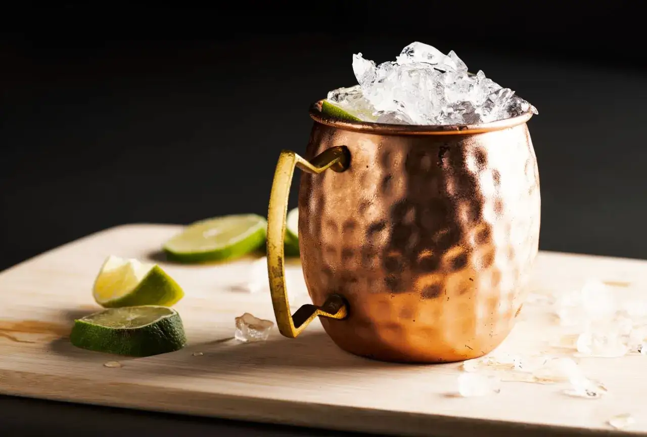 Ein Moscow Mule im Kupferbecher, gefüllt mit Eis und Limettenspalten. Die Herkunft des Drinks ist ein interessantes Detail.