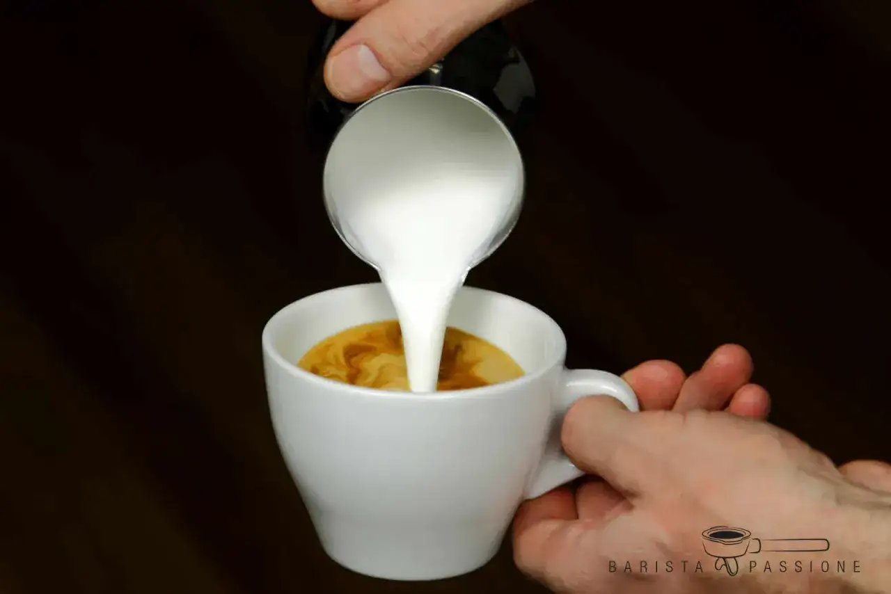 Milch wird in eine Tasse mit Espresso gegossen, um einen Cappuccino zuzubereiten. Die Frage