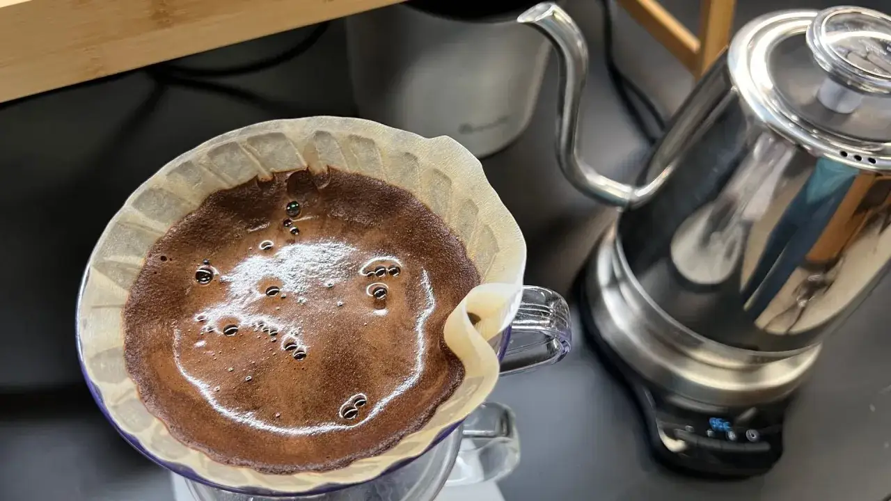 Frisch gemahlener Kaffee wird langsam mit heißem Wasser aufgegossen, um das Aroma zu extrahieren. Der Prozess des Kaffee filterns beginnt.