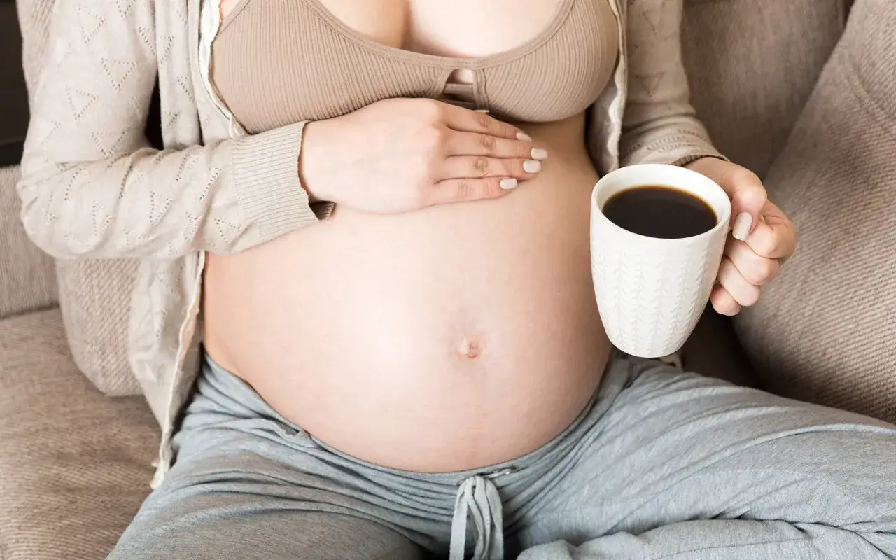 Schwangere Frau hält eine Tasse Kaffee. Die Frage