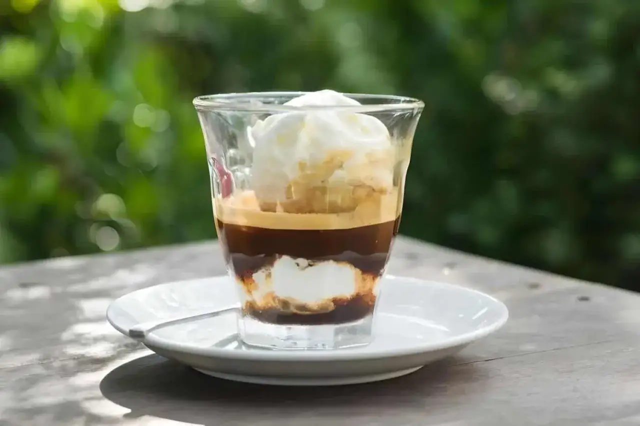 Ein Glas mit einem Schichtdessert aus Espresso und cremigem cafe eis.
