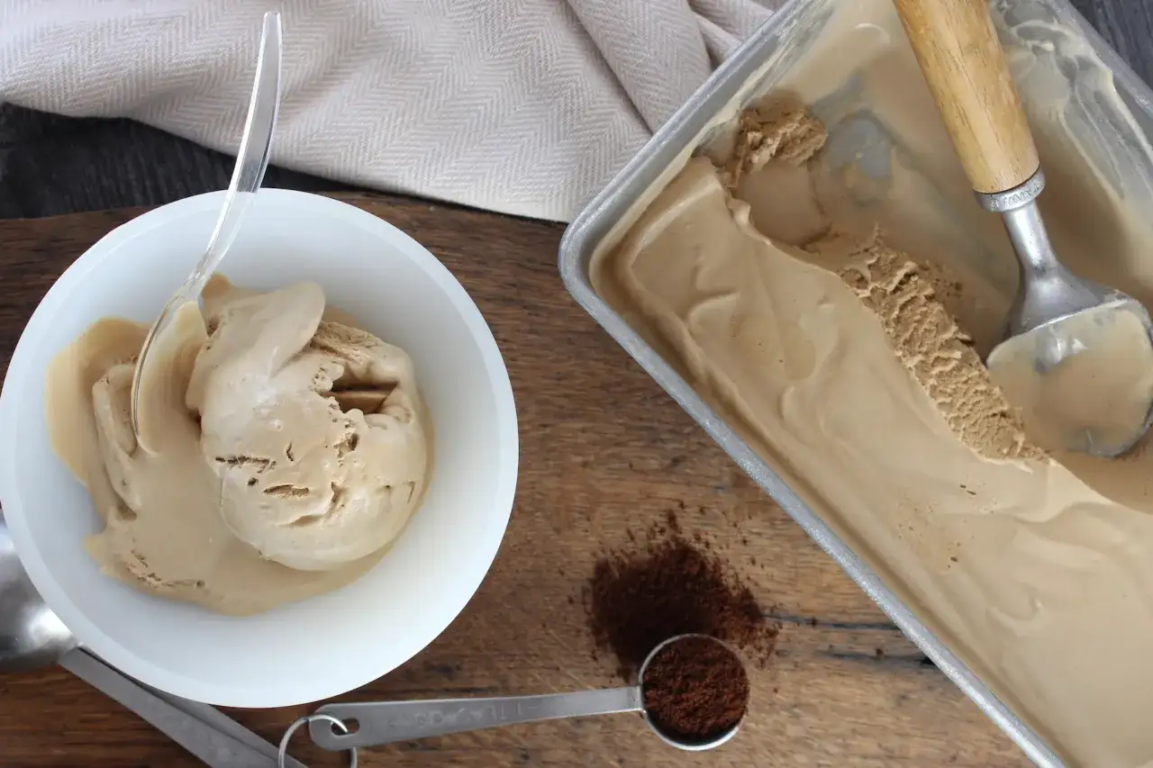 Kaffee Eis Rezept: Cremiges Eis in einer Sch&uuml;ssel und im Beh&auml;lter, mit Kaffeepulver daneben.