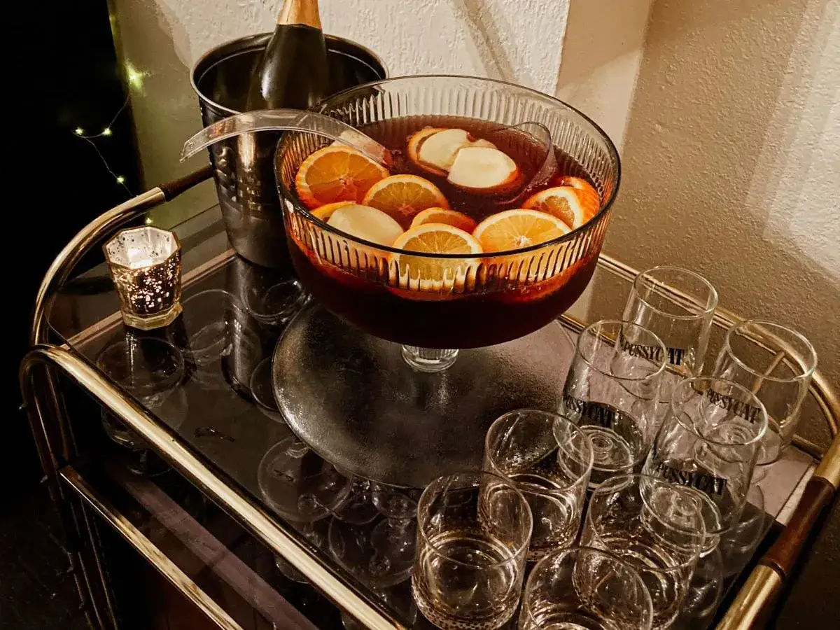 Fruchtiger Punsch in einer Schale, bereit für einfache Cocktails Rezepte. Daneben Gläser und eine gekühlte Flasche.