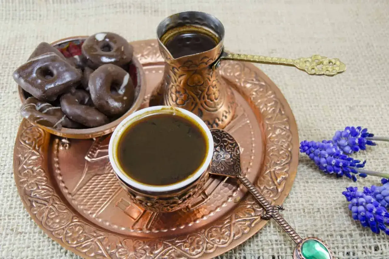 Ein traditionelles Kupfer-Set mit mokka kaffee, Schokoladenkeksen und blauen Traubenhyazinthen.